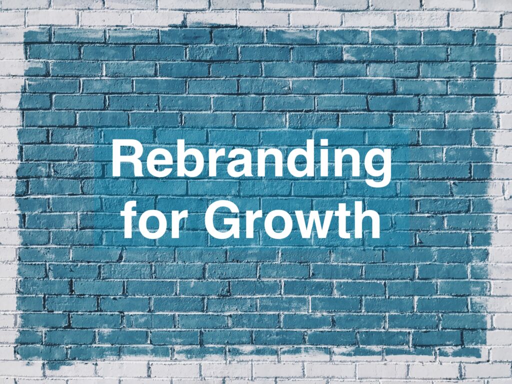 A brick wall with a freshly painted blue rectangle, displaying the text 'Rebranding for Growth'