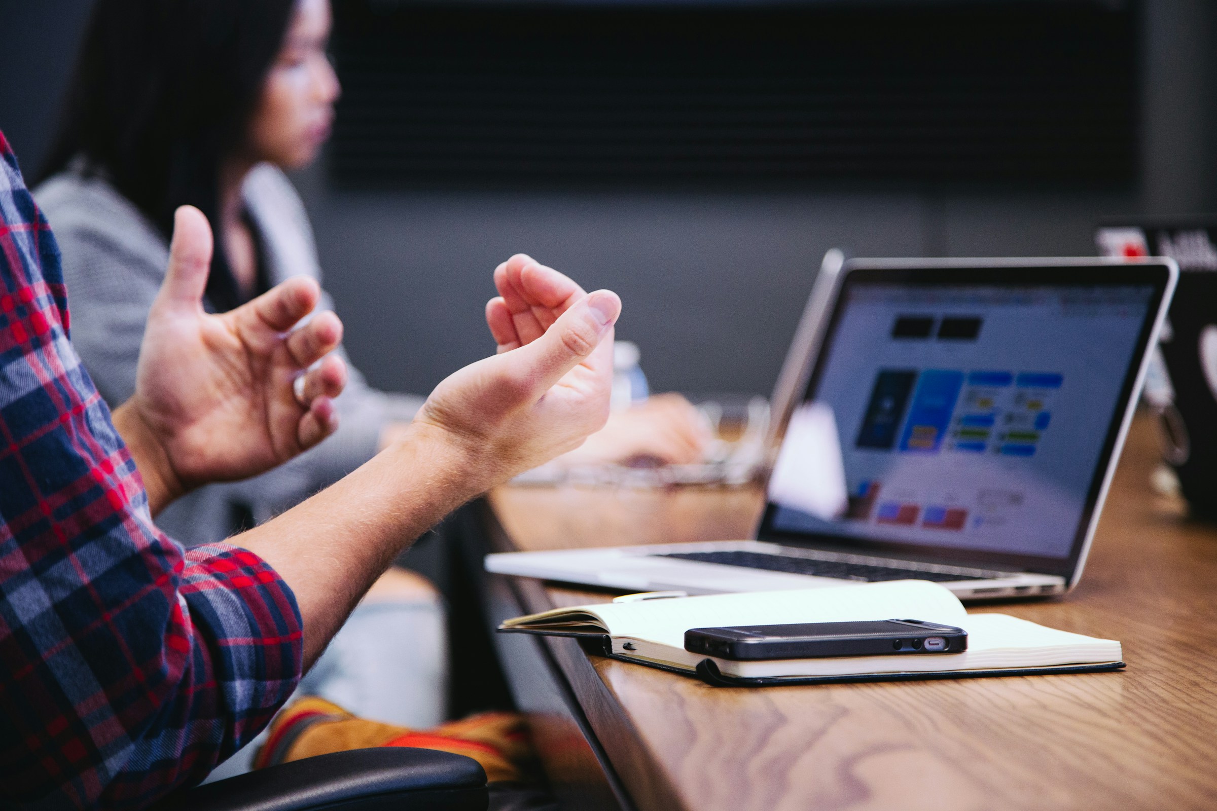 Overcoming Sales Objections: Two professionals discussing over a table, with one person explaining technical details to another in a high-tech sales environment.