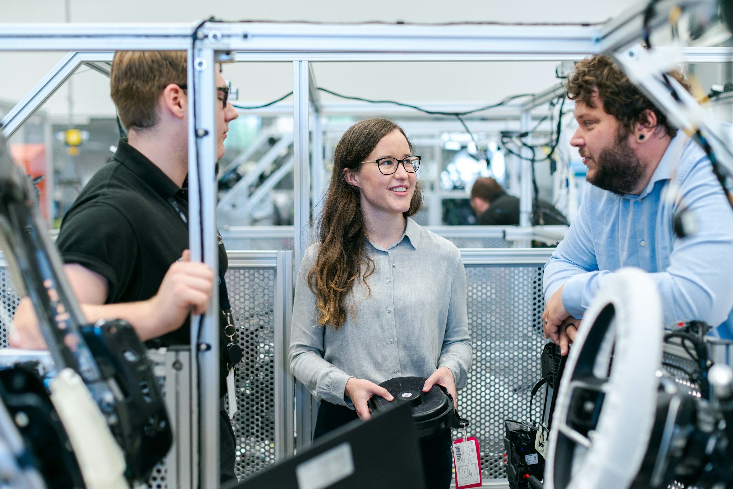 Reengaging High-Tech Customers: Sales engineer and scientists discussing in a lab, all smiling and engaged in conversation.