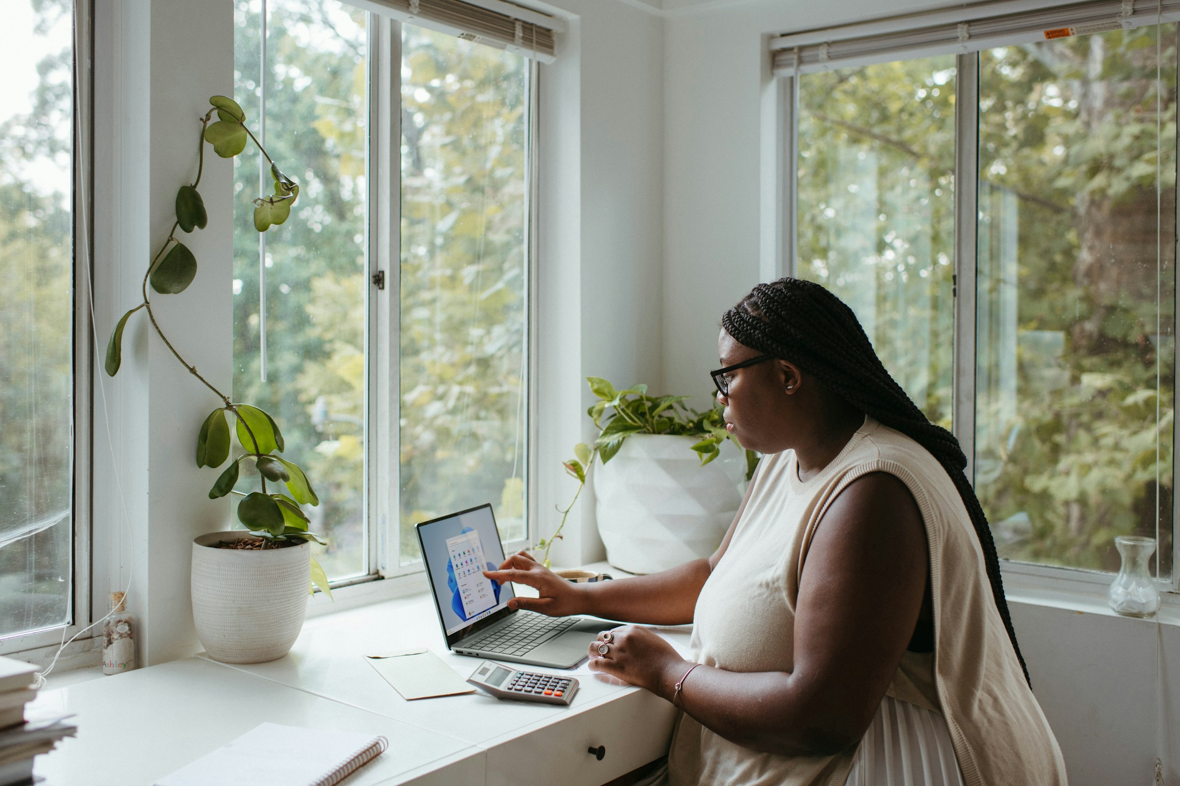 Remote Sales Team Management: Remote worker in a home office setting, focused on a laptop with organizational tools visible.