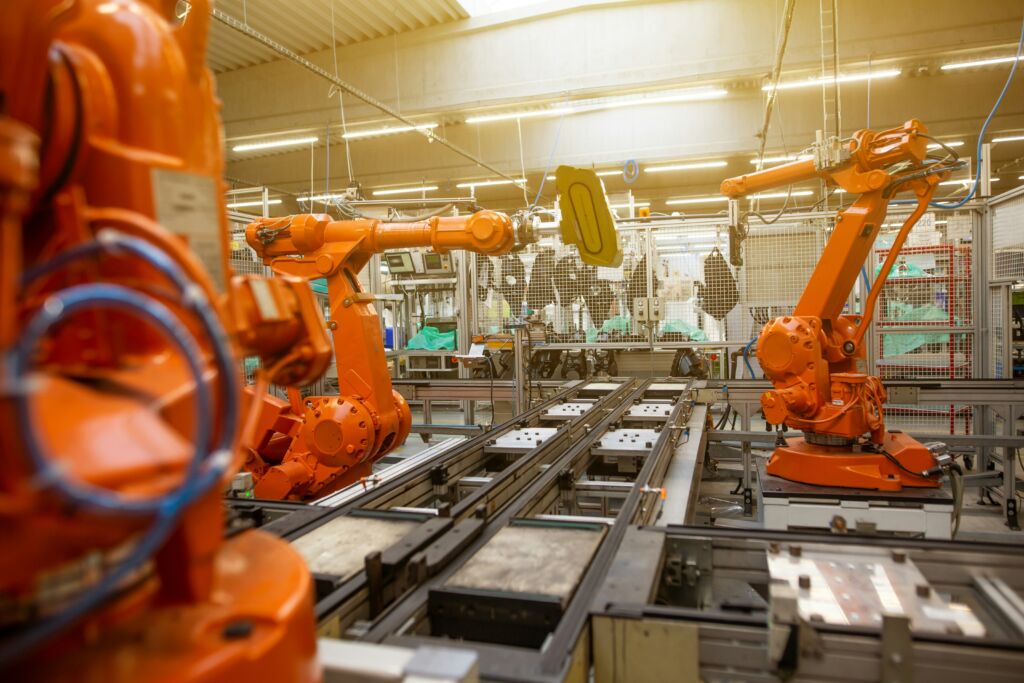 Scaling Manufacturing Business: Robotic arms in a modern manufacturing plant indicating advanced technology and automation.